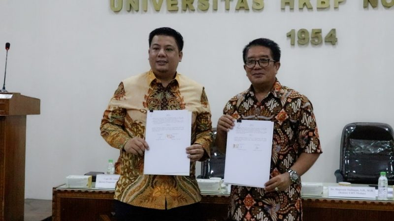 Rektor Universitas HKBP Nommensen Medan Dr. Haposan Siallagan, S.H., M.H dan Bupati Kabupaten Samosir, Vandiko Timotius Gultom, S.T berfoto bersama sambil memegang dokumen kerja sama.(Sumber: Nella H/PM).